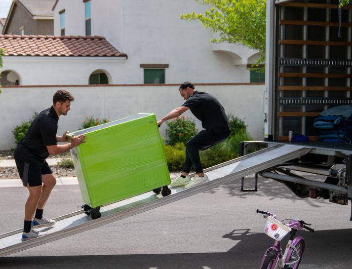 Two men loading green furniture onto moving truck